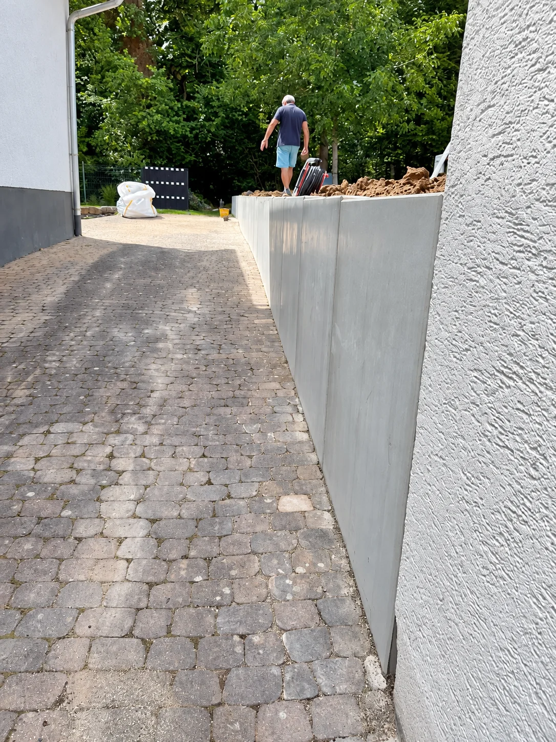 Betonelemente entlang eines gepflasterten Wegs während der Bauphase.