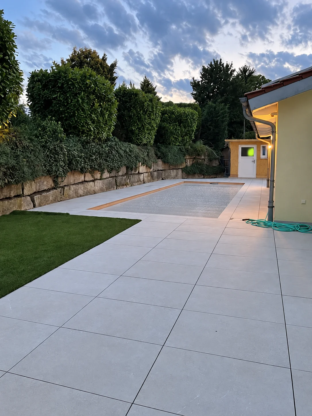 Großformatige Platten, Rasen und Einfassung im Garten.